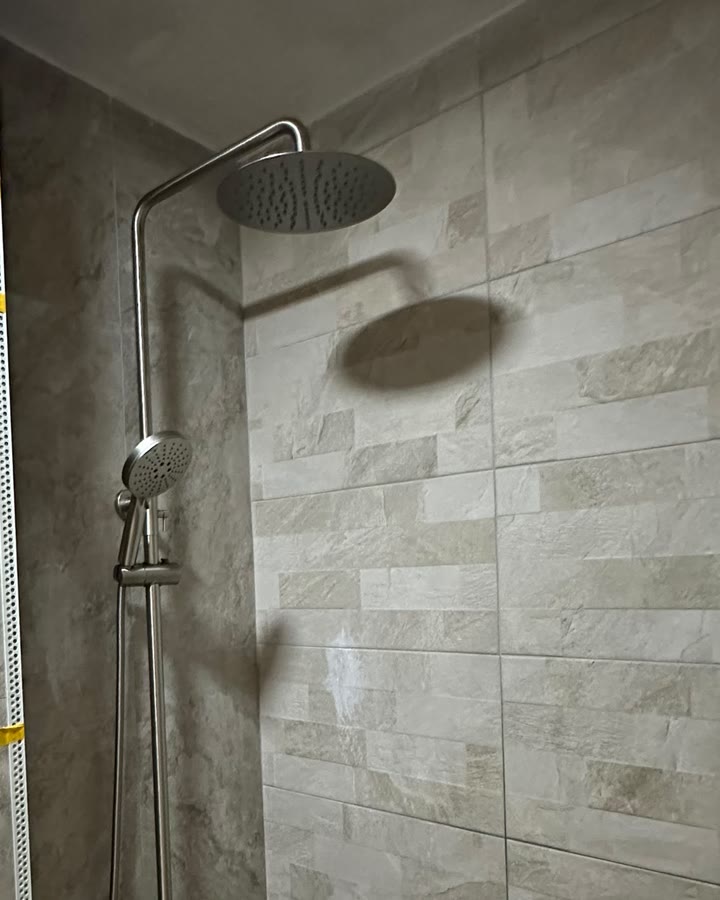 Rainfall shower set installed on a marble-tiled wall